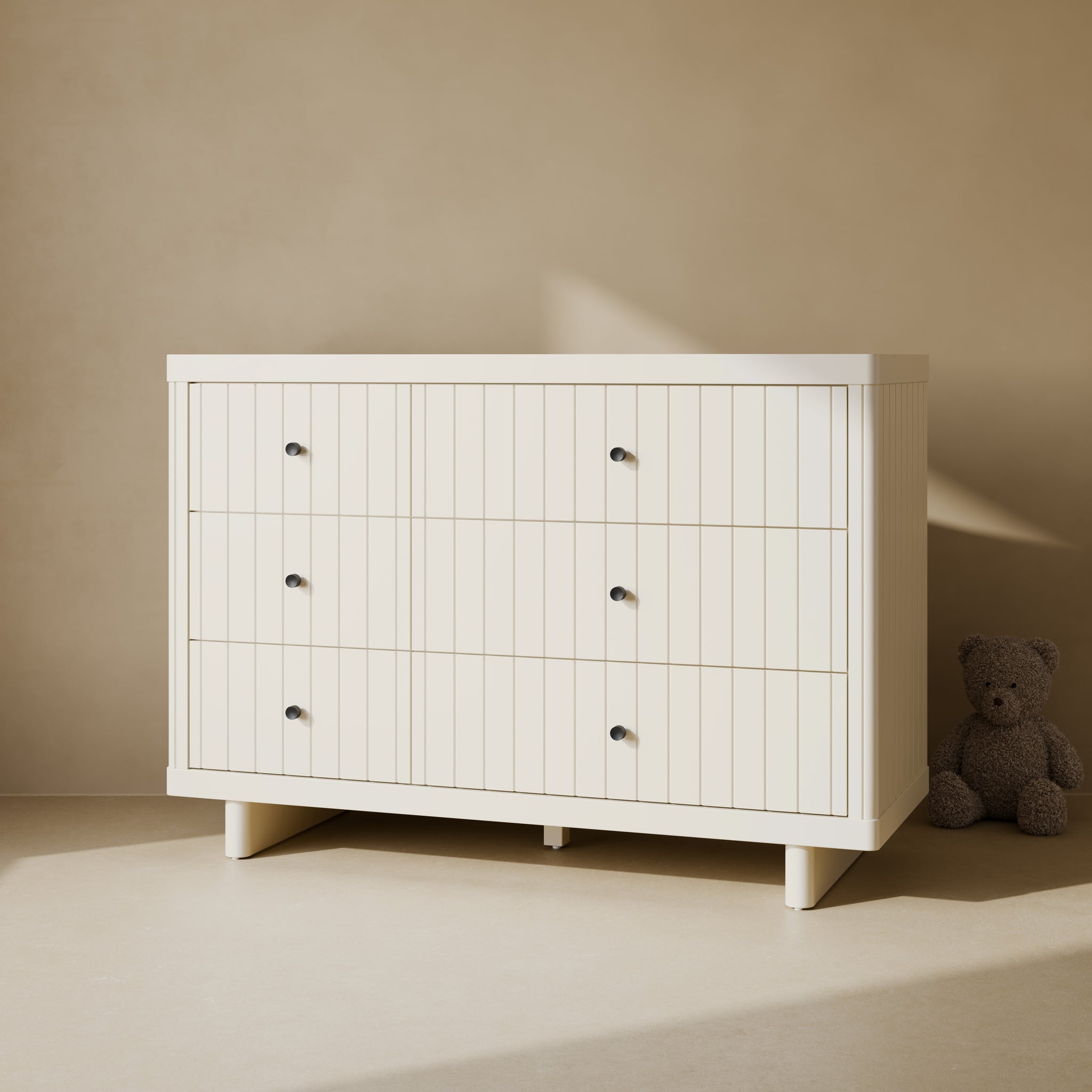 Beige 6 drawer dresser with asymmetrical drawers in room with teddy bear on floor