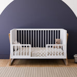 white and vintage driftwood crib toddler bed conversion with two guardrail in nursery