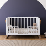 white and vintage driftwood crib toddler bed conversion with two guardrail in nursery