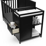 Close-up view of black crib and changer with open drawer