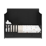 Black crib with drawer in toddler bed conversion with one safety guardrail