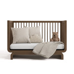 santorini hazelnut crib daybed conversion with blanket, pillows, and teddy bear