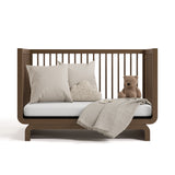 santorini hazelnut crib daybed conversion with blanket, pillows, and teddy bear