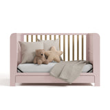 Read-with-Me crib blush with driftwood daybed conversion with pillows, stuff toys, and a blanket