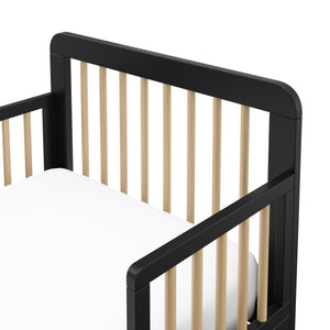 Detail view of a black toddler bed with driftwood finish