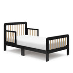 Angled view of a black toddler bed with driftwood finish