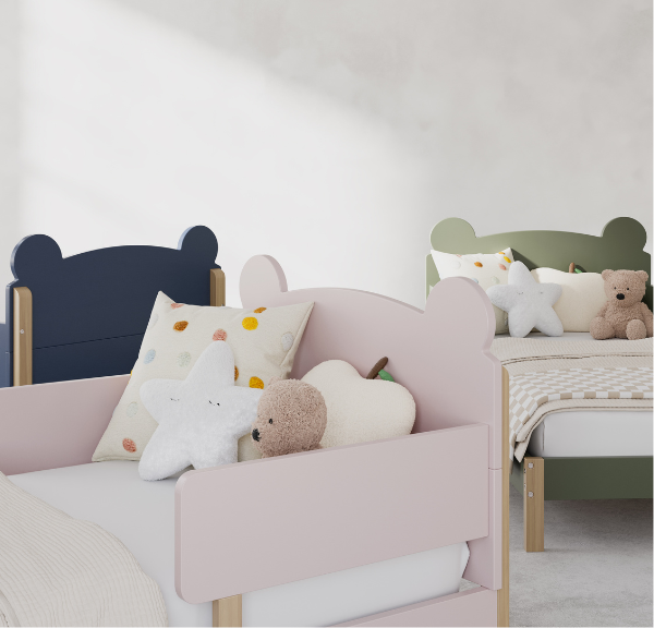 Three toddler beds with teddy bear shaped headboards, positioned at differing angles, in multiple colors ranging from navy blue, light pink, and olive green