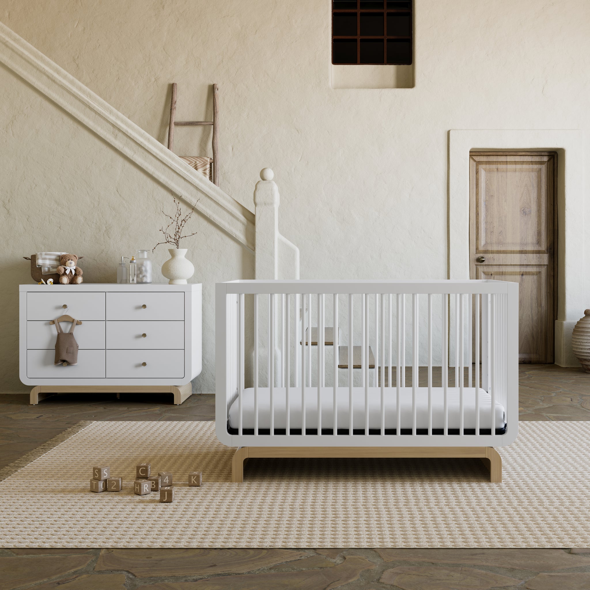 Two-tone white and natural wood baby crib and six drawer dresser collection in a rustic room setting